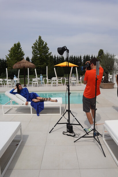 Behind-the-scenes outdoor photography setup with studio lighting rig and subject in blue.
