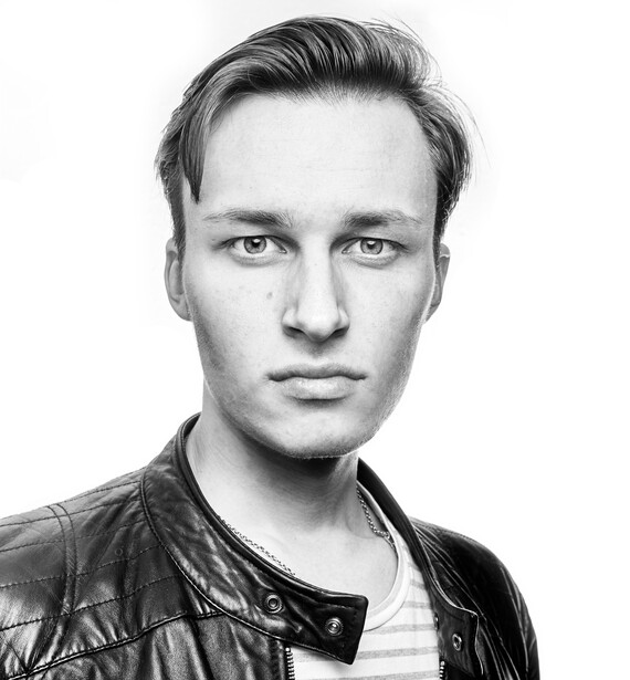 Black and white portrait of a young man with swept-back hair wearing a leather jacket over a striped shirt.