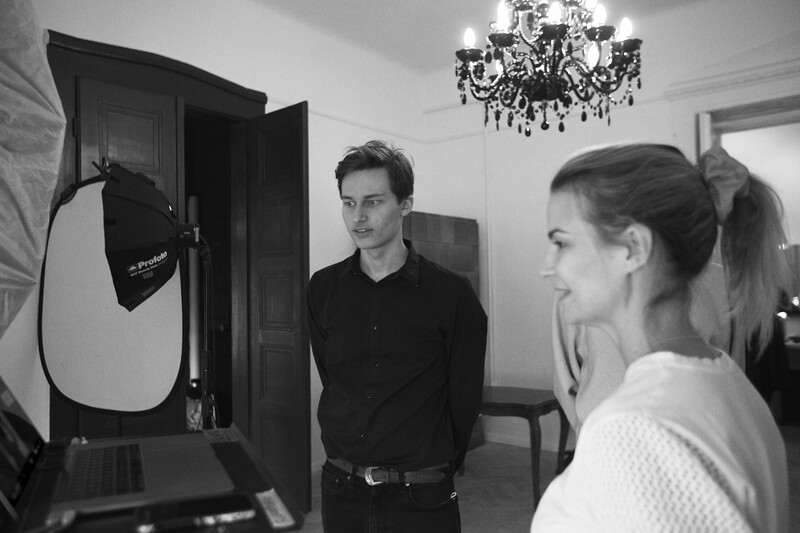 Two people in an elegant room with a photography lighting setup featuring a softbox on the left side.