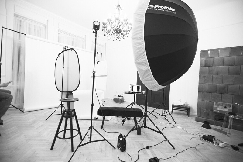 Professional studio setup with large parabolic softbox, key light, and fill reflector arranged around a central shooting area.