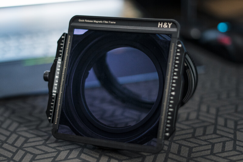 H&Y brand square filter holder with magnetic attachment system and mounted lens element on patterned surface.