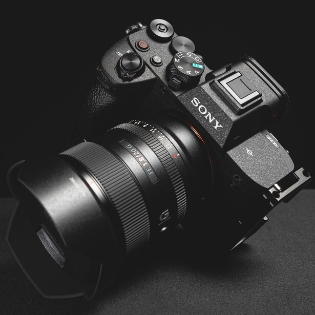 Sony mirrorless camera with attached lens and hood on dark surface.