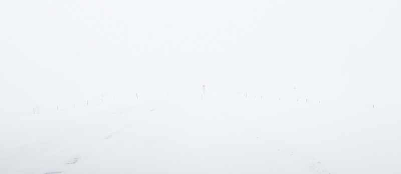 Minimalist landscape with vertical fence posts emerging from fog or mist.