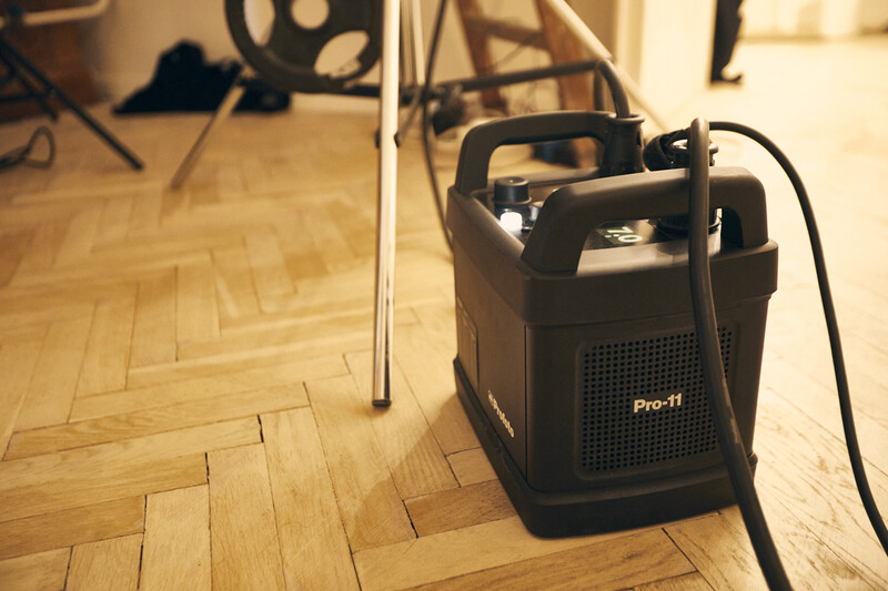 Black Pro-11 portable generator sitting on herringbone wood flooring in a studio setting.