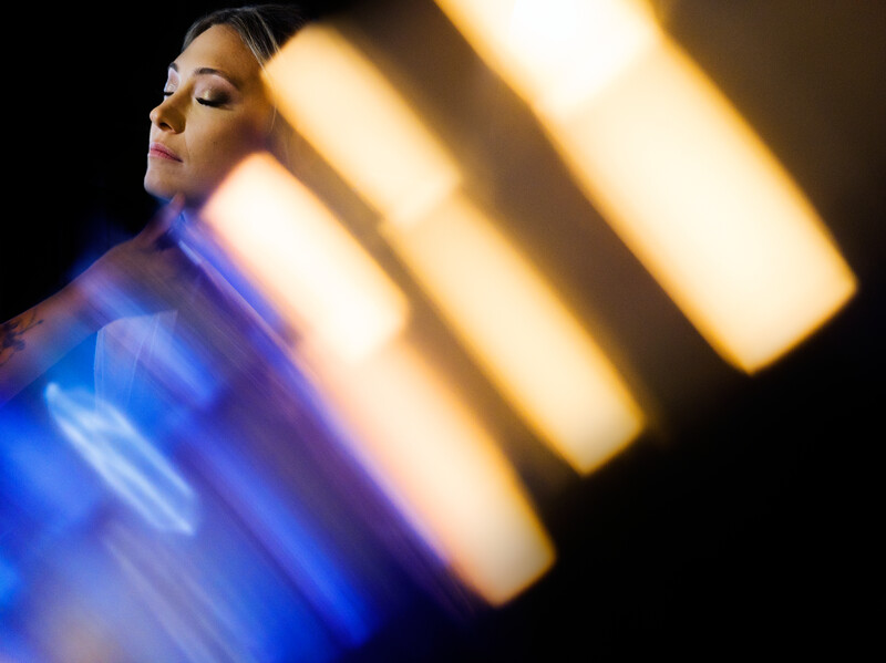 Woman in profile against blurred blue and warm golden rectangular light sources.