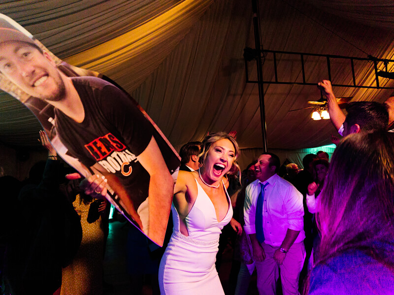 Woman in white dress laughing at indoor event with large video screen and purple ambient lighting.