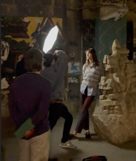 Photographer shooting a portrait of a woman against a stone wall under bright studio lighting.