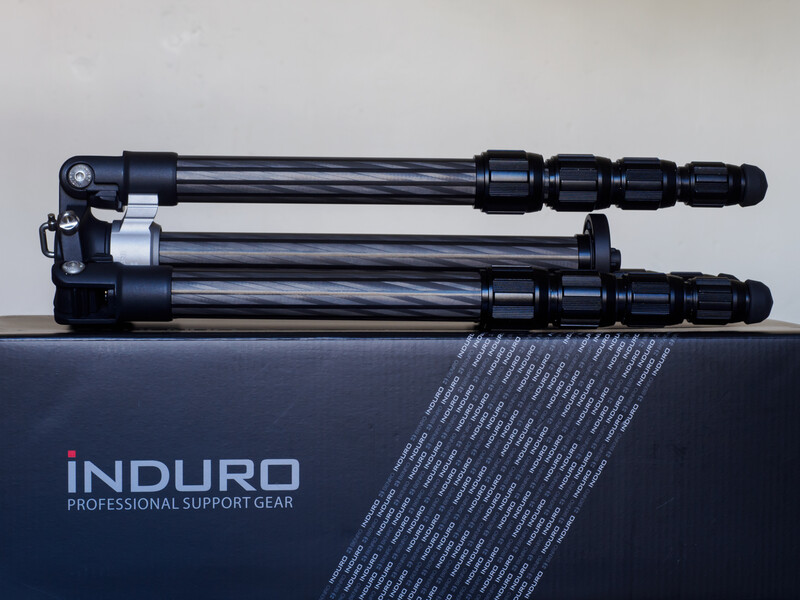 Induro tripod with three black leg sections and center column displayed on dark packaging box.