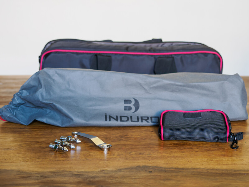 Induro camera gear bag opened to display compartments, with small accessories and lens caps arranged nearby on wooden surface.