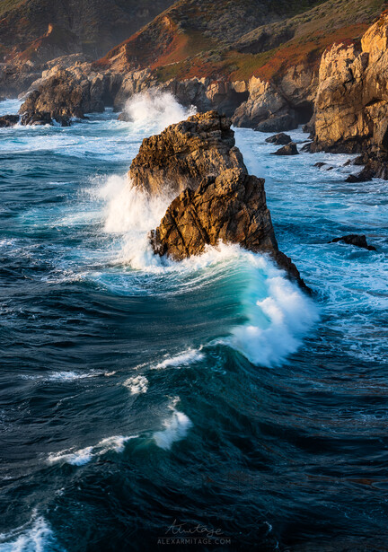 Waves crash against jagged golden rock formations along a dramatic coastal cliff at golden hour.