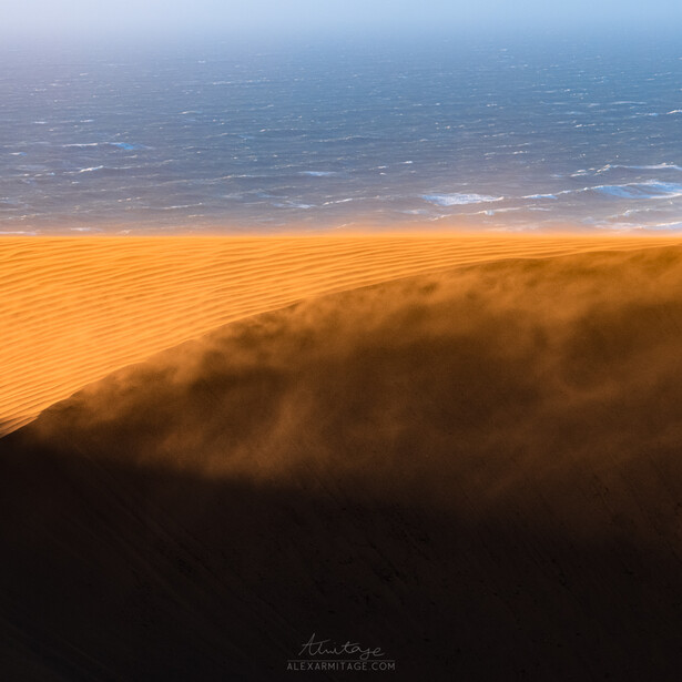 Shadow of a mountain peak cast across golden and blue landscape during sunrise or sunset.