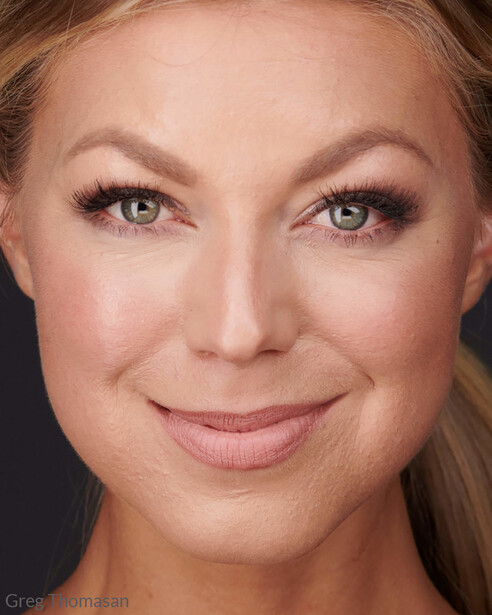 Headshot of a woman with neutral expression against dark background.