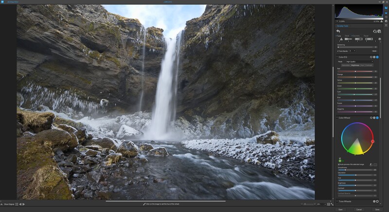 Waterfall cascading down rocky cliffs surrounded by snow and moss-covered stone.