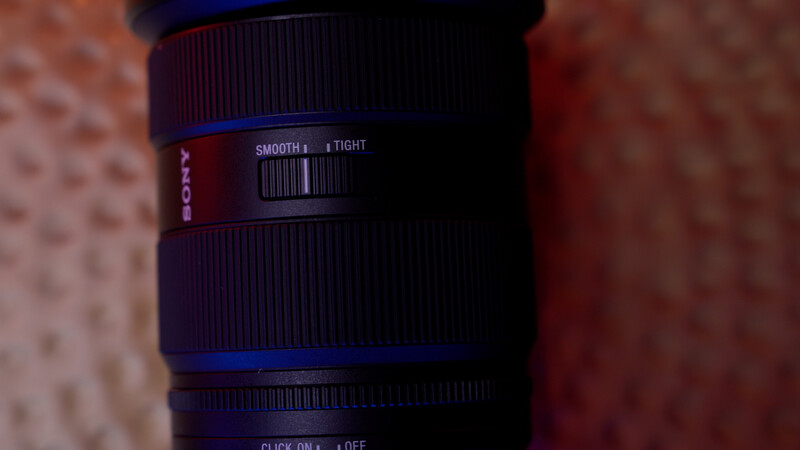 Close-up of a camera lens barrel showing smooth focus ring and tight autofocus markings.