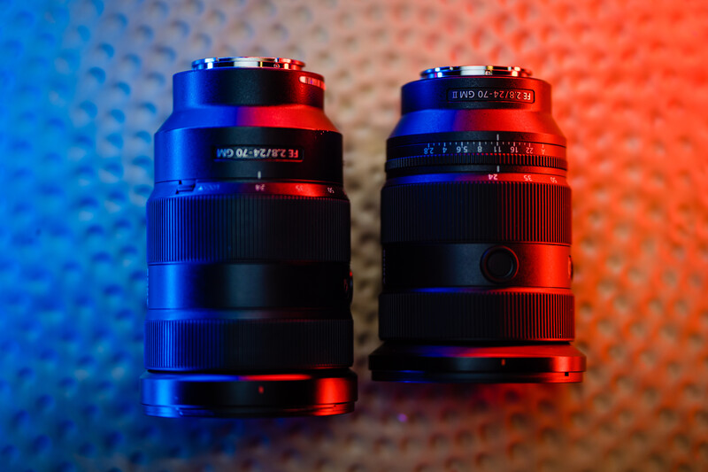 Two vintage camera lenses side by side, illuminated by contrasting blue and red gel lighting against a textured background.