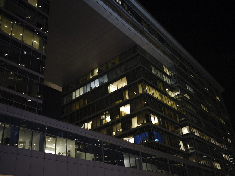 Illuminated office building windows at night showing warm interior lighting against dark sky.