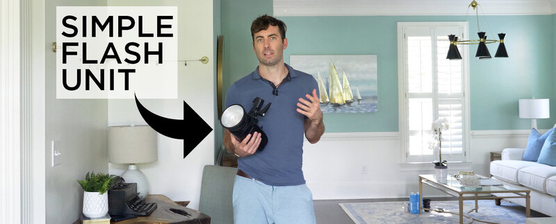 Man in blue shirt holding a simple flash unit while teaching in a modern living room.