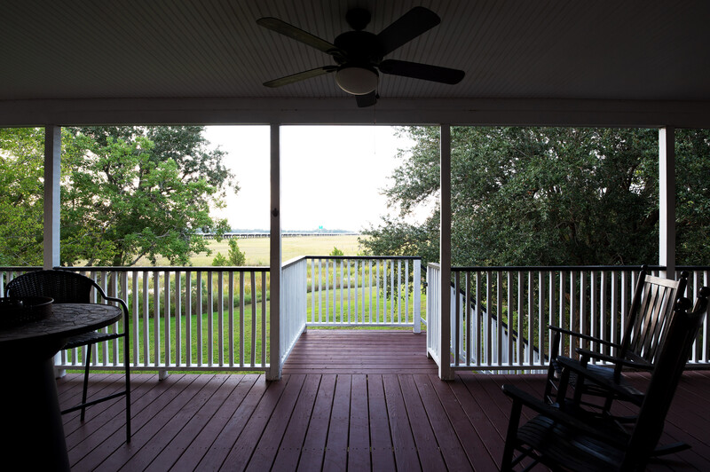 Interior view of a covered porch looking out toward a rural landscape through large windows and glass doors.