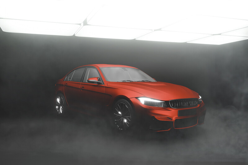 Red sedan automobile photographed against dramatic dark background with atmospheric fog effect.