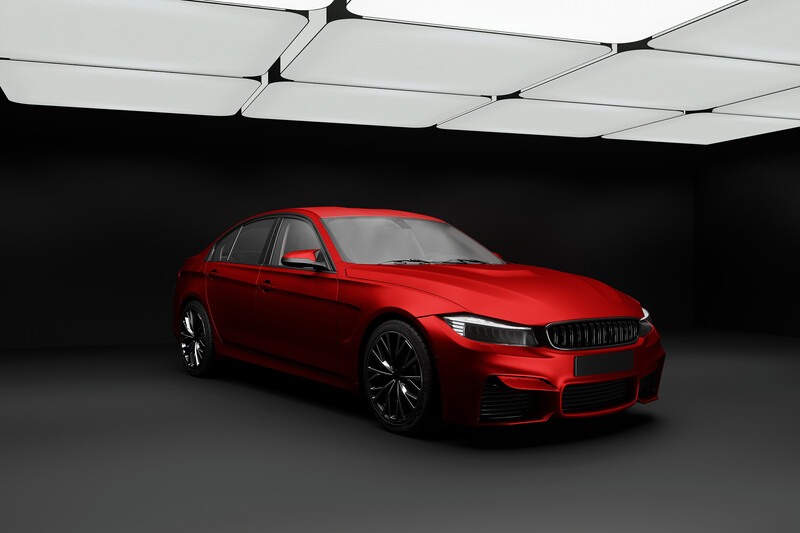Bright red sedan shot against dark background with geometric ceiling lighting.