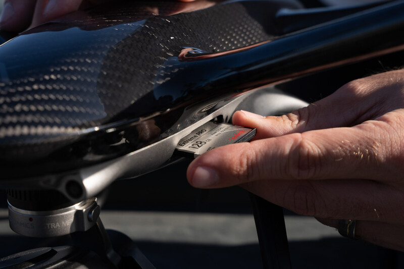 Photographer's hands adjusting a camera's control dial in bright sunlight.