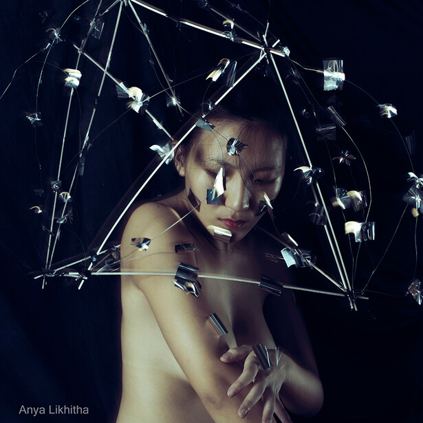 Shirtless person surrounded by geometric wireframe network lines and floating technological elements against dark background.