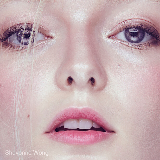 Close-up portrait of a fair-skinned face with blue eyes, pink lips, and soft studio lighting.