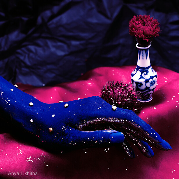 Hand painted with blue and gold glitter against pink fabric, holding a decorative perfume bottle with red flowers.
