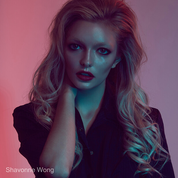 Portrait of a woman with long blonde hair against a pink and teal gradient background.