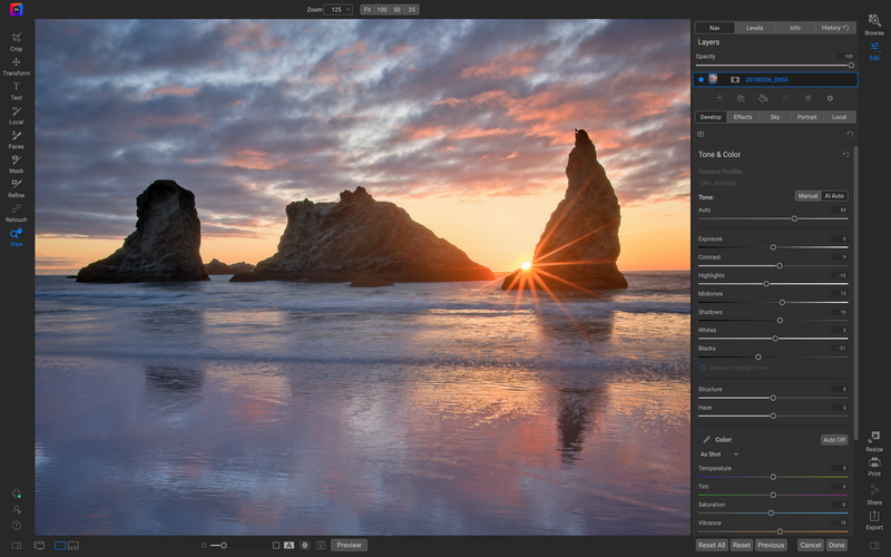 Sunset seascape with three sea stacks silhouetted against golden sky and reflecting in wet sand.