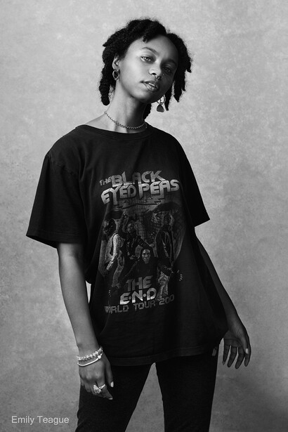 Black and white portrait of a person wearing a graphic band t-shirt, photographed against a plain backdrop.