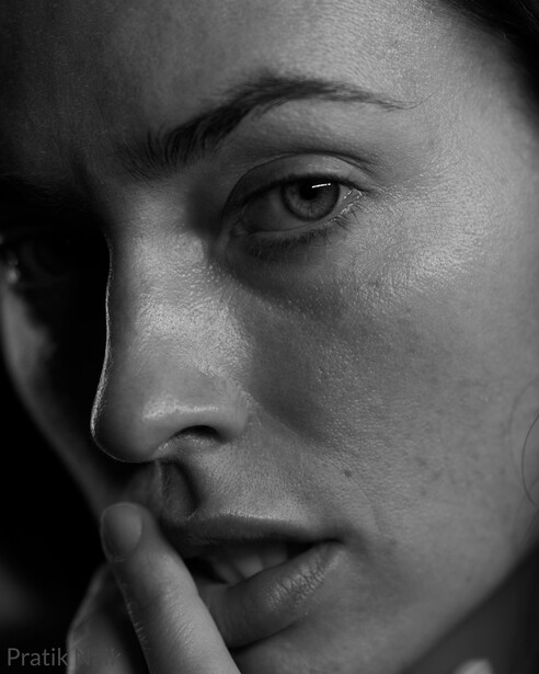 Black and white close-up portrait of a person's face with hand touching cheek, contemplative expression.