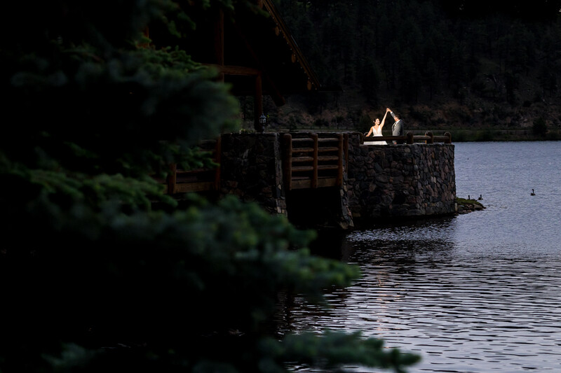 Stone structure with wooden gate on water's edge at dusk, illuminated by warm light.