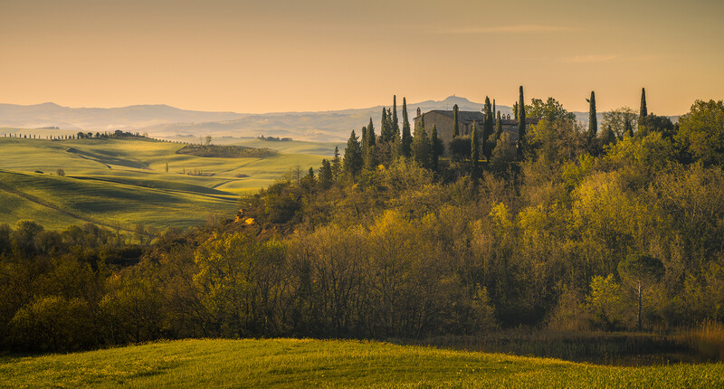 Rolling Tuscan hills at golden hour with a villa nestled among cypress trees and autumn foliage.