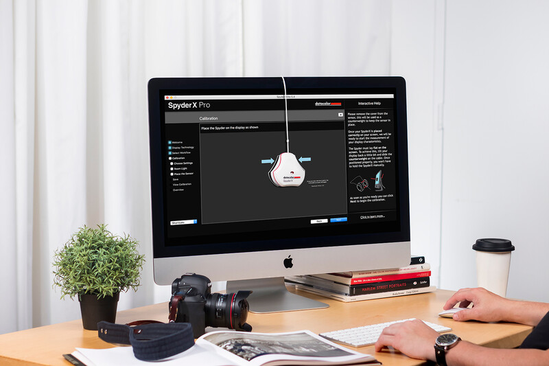 Photographer's workspace featuring an iMac displaying Spyder X Pro color calibration software.