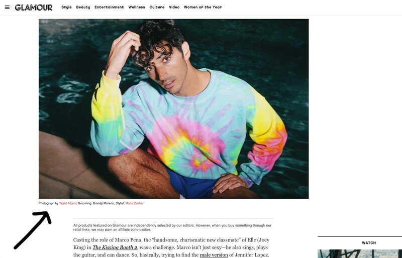 Portrait of a person wearing a tie-dye sweatshirt with pastel rainbow colors, posed against dark water.