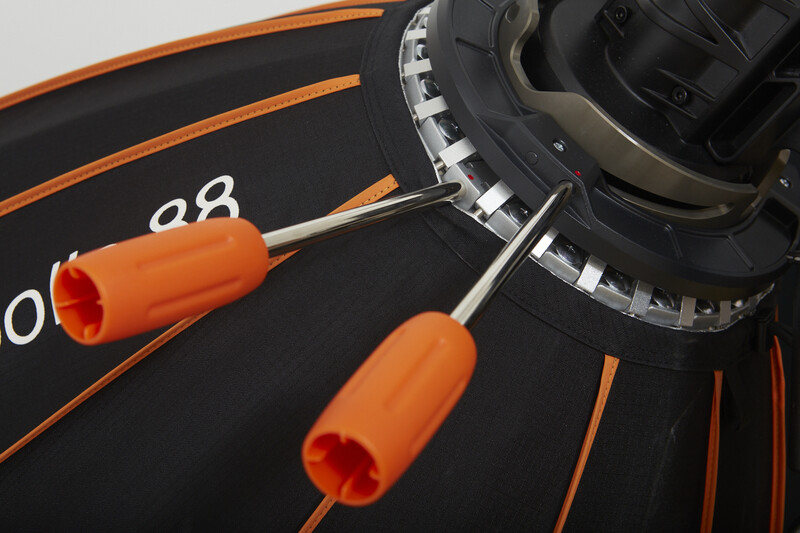 Close-up of a dartboard with orange trim and two orange-handled darts positioned near the center.