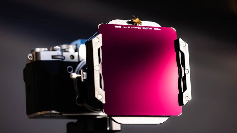 Large format camera with magenta filter attached to lens assembly.