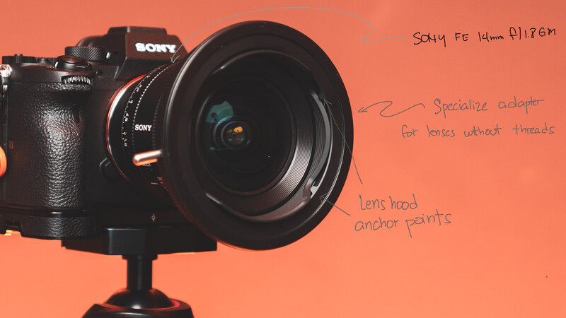 Sony A7 camera with wide-angle lens mounted on tripod against coral background.
