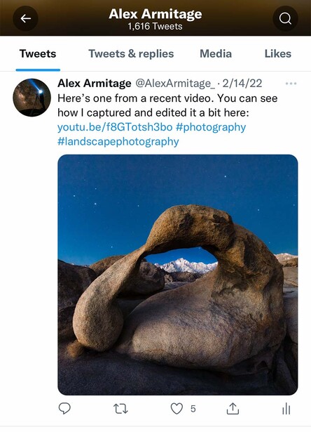 Rock formation framing a snow-capped mountain peak against deep blue sky.