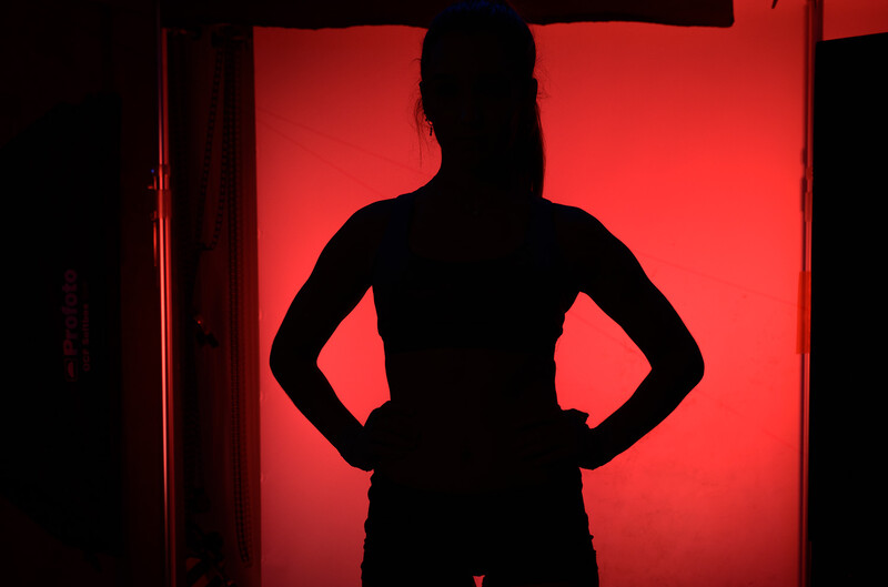 Silhouetted figure standing with hands on hips against a vibrant red backlit background.