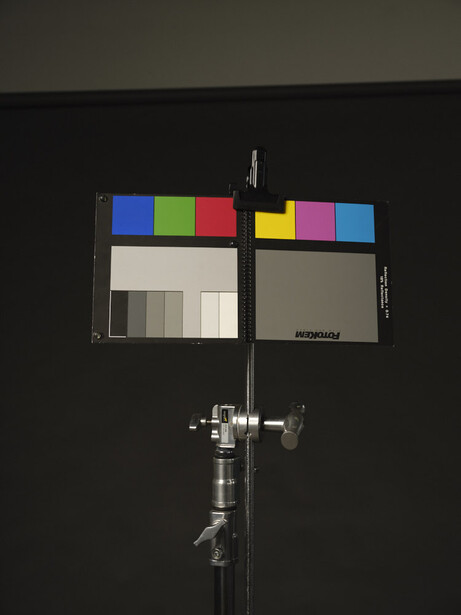 Color checker reference card mounted on a studio stand against a dark background.