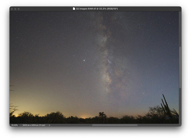 Milky Way galaxy stretching vertically across a dark sky above a desert landscape at twilight.