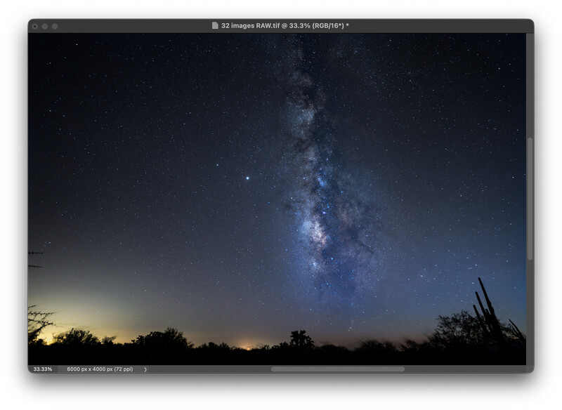 Milky Way galaxy stretching vertically across a dark night sky above a silhouetted desert landscape with scattered vegetation.