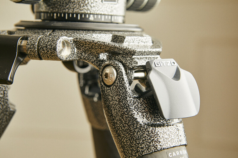 Close-up of a vintage 1911-style pistol with speckled textured finish and white grip panel against neutral background.