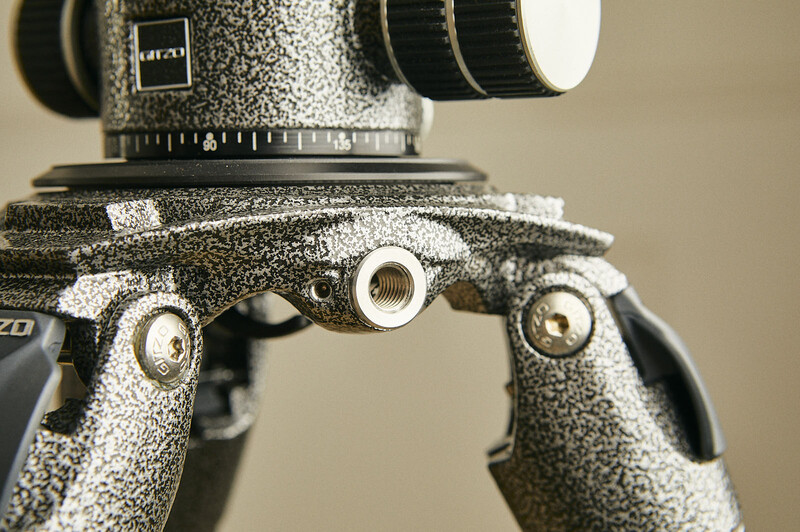 Close-up of a tripod head's handle and mounting plate with textured surface coating.