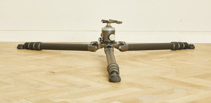 Vintage tripod with brass fittings and wooden leg wraps displayed on wooden flooring.