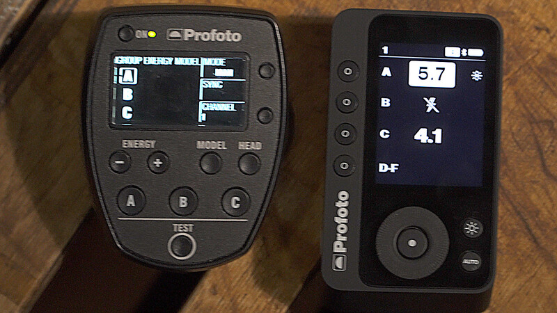 Two Profoto wireless flash trigger remotes displayed side by side on a wooden surface.