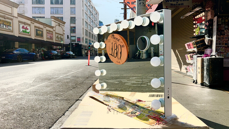 DIY vanity mirror with round bulbs and wooden frame on urban street.