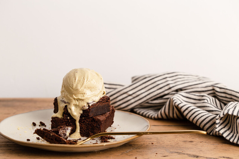 Chocolate cake slice topped with vanilla ice cream on a white plate with striped cloth.